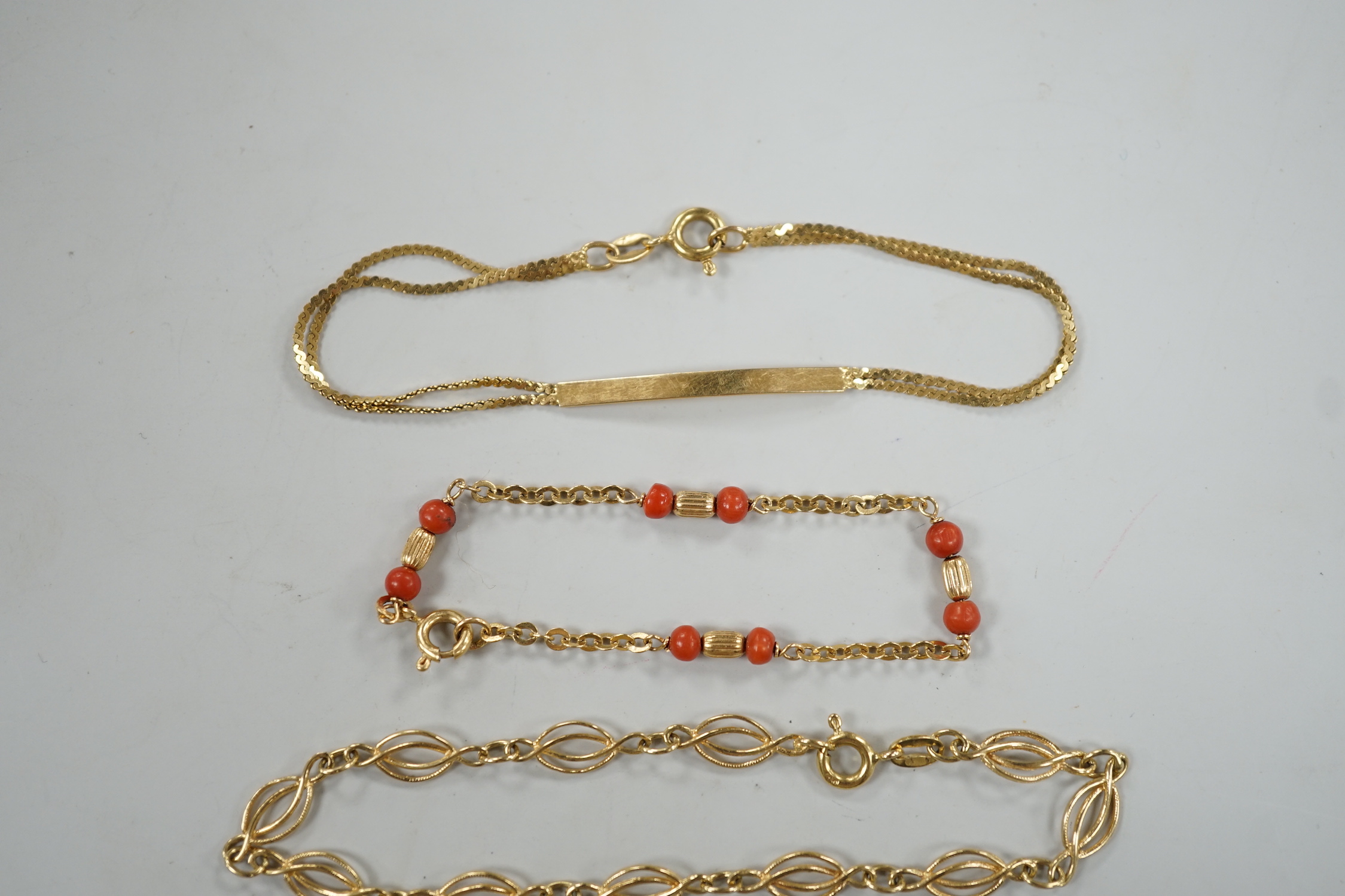 Four assorted 20th century 750 yellow metal bracelets, including child's with coral beads, 13cm